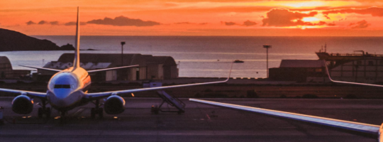 A Parked Airplane With A Sunset Above The Sea At The Background